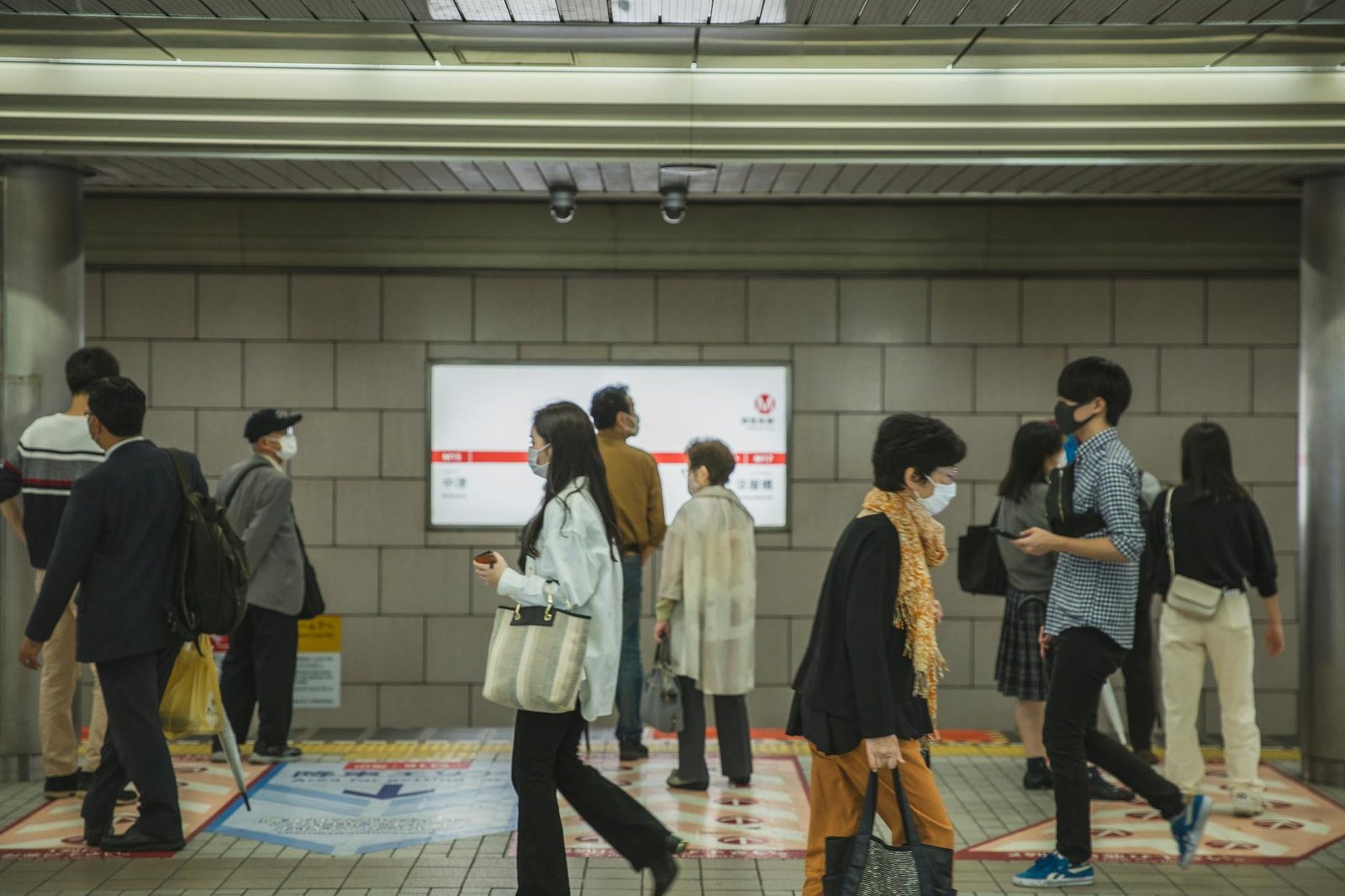 ethnic people walking in underground passage in masks